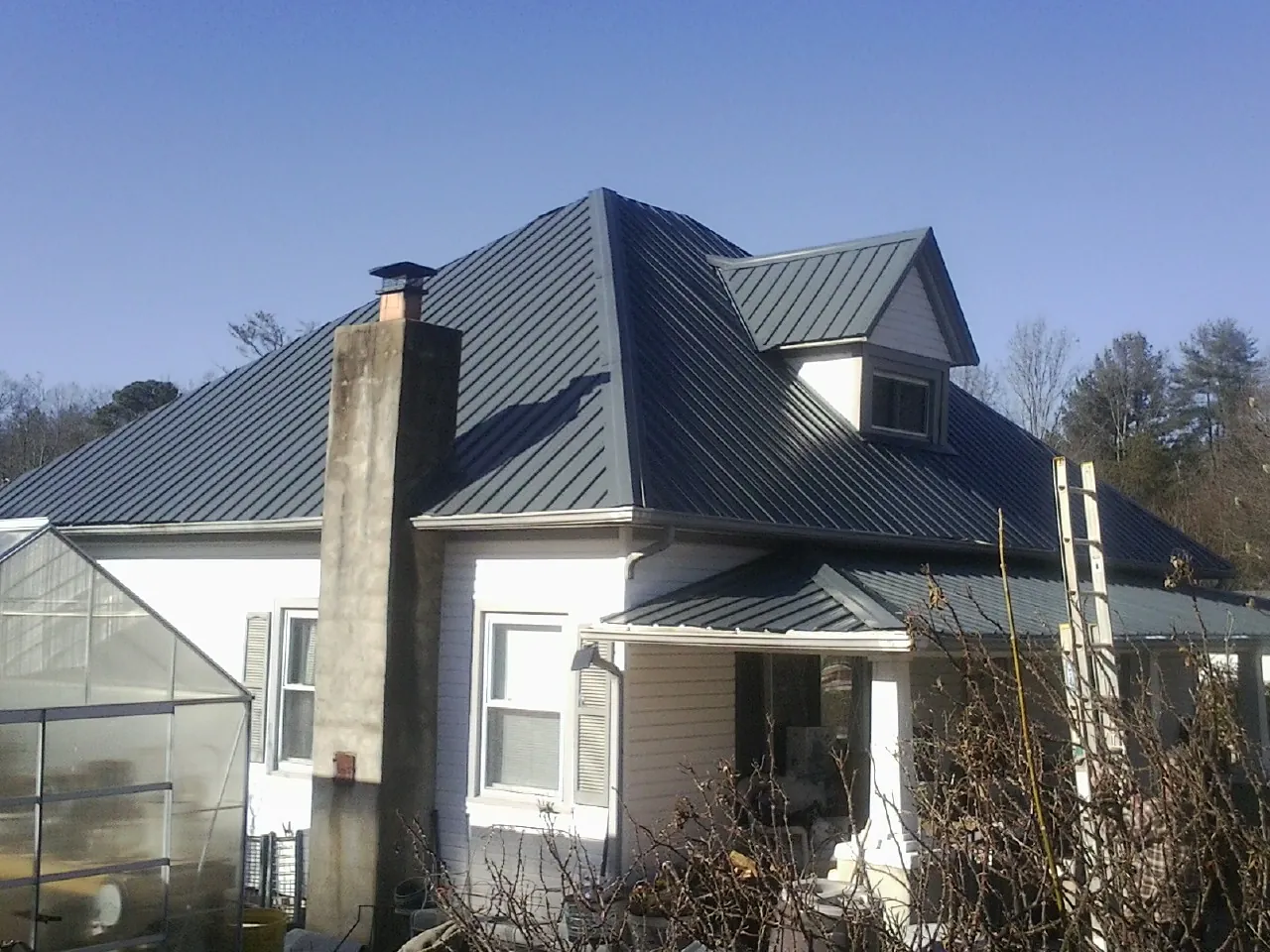 Dark blue standing seam metal roof on a white farmhouse with dormer — Slate & Tile Roof Repair by Roofing Brothers in Nicollet