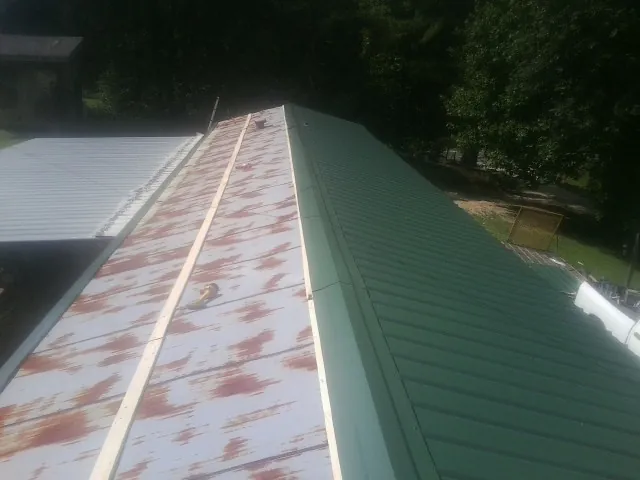Old rusted panels beside newly installed green metal roofing — Wind Damage Roof Repair by Roofing Brothers in Nicollet