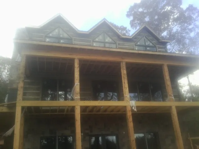 Dormers and porch framing on a large log home under construction — Roof Coating work by our crew in Nicollet