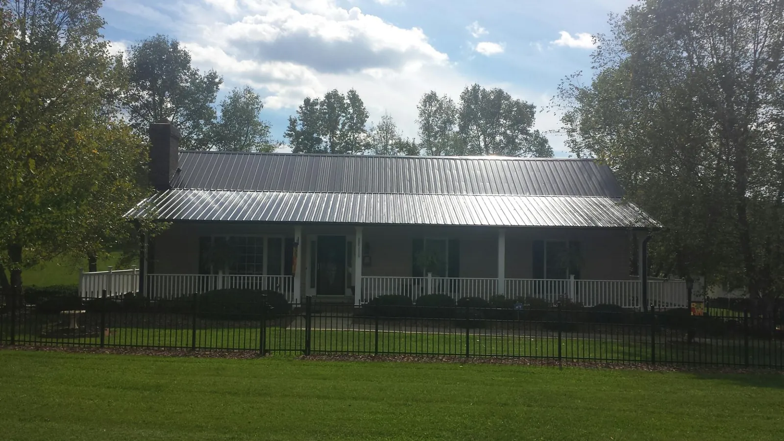 Gray metal roof on a brick ranch with a full width front porch — Gutter Guard Installation work by our crew in Nicollet
